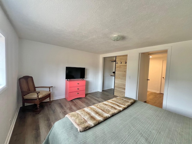 bedroom with a textured ceiling, baseboards, and wood finished floors