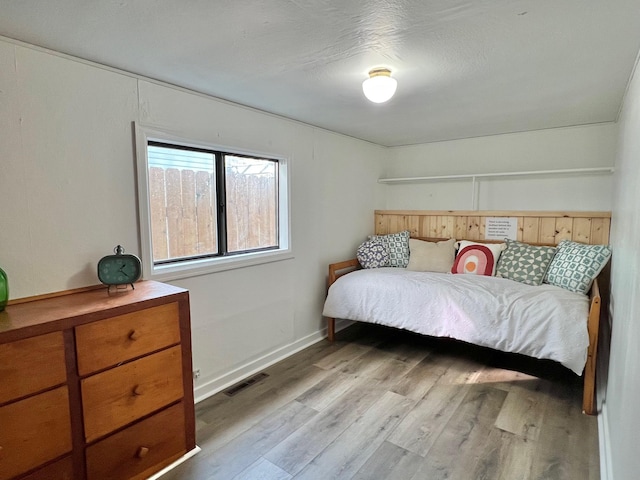 bedroom featuring visible vents, baseboards, and wood finished floors