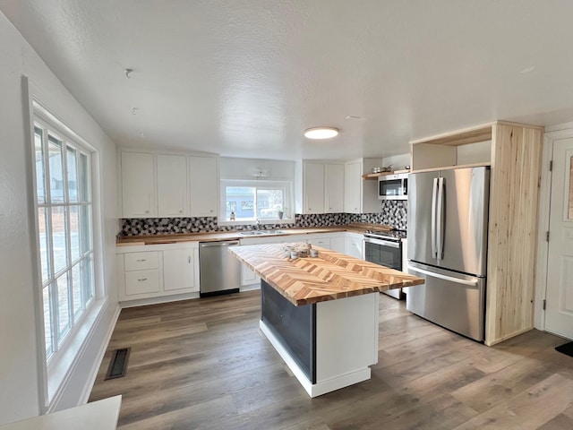 kitchen featuring wood finished floors, wooden counters, open shelves, stainless steel appliances, and white cabinets