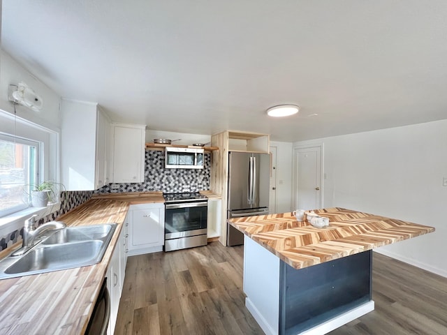 kitchen featuring a sink, stainless steel appliances, wood counters, and open shelves