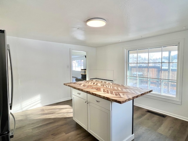 kitchen featuring dark wood-style floors, visible vents, wooden counters, and freestanding refrigerator