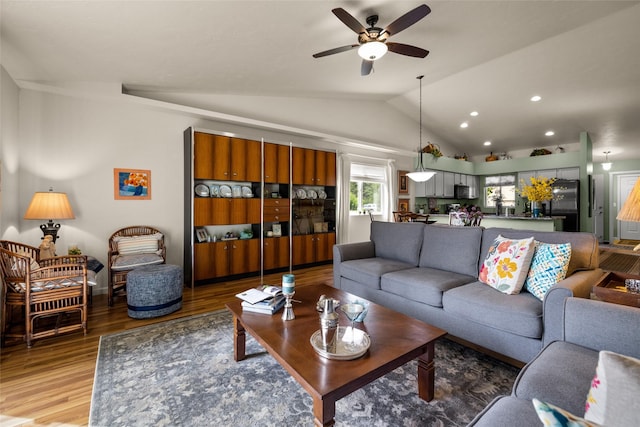 living room featuring ceiling fan, vaulted ceiling, and wood-type flooring