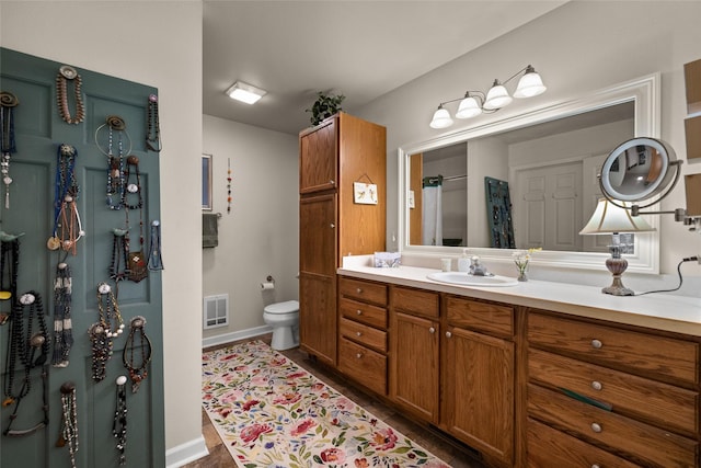 bathroom with toilet, vanity, and tile patterned flooring