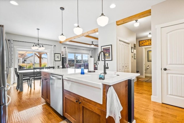 kitchen with sink, hanging light fixtures, a center island with sink, and stainless steel appliances