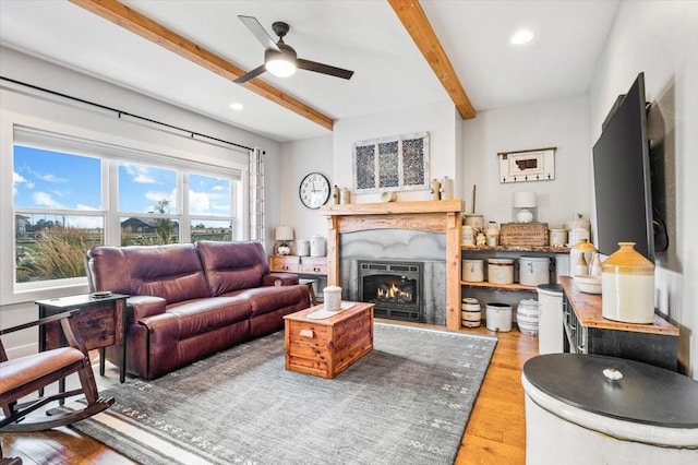 living room with ceiling fan, wood-type flooring, and beamed ceiling