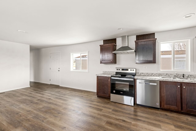 kitchen featuring a wealth of natural light, wall chimney exhaust hood, sink, and stainless steel appliances