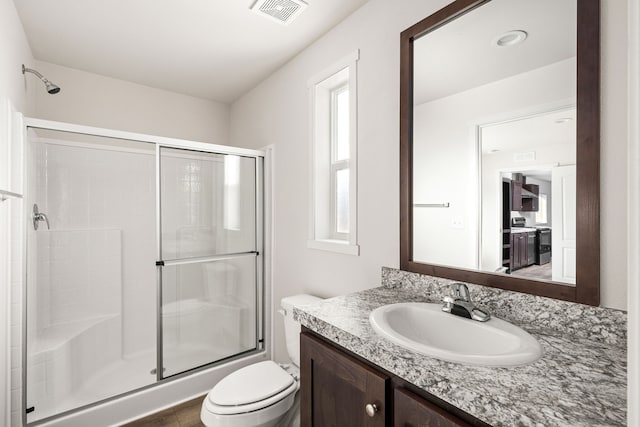 bathroom with a wealth of natural light, an enclosed shower, vanity, and toilet