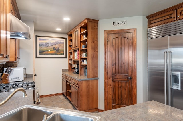 kitchen featuring light tile patterned floors, sink, stainless steel built in refrigerator, and exhaust hood