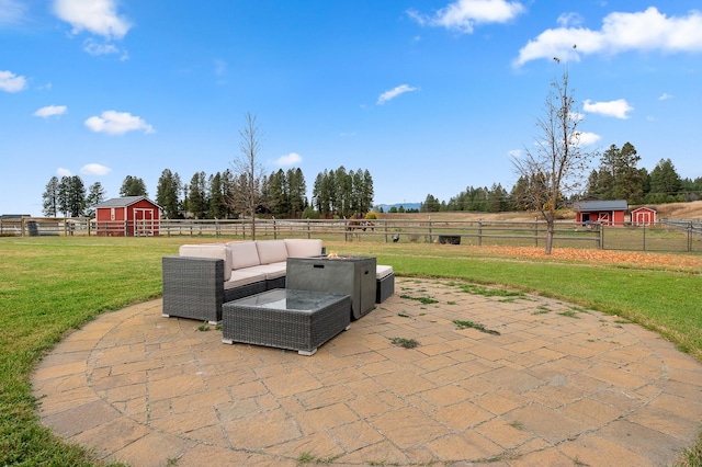 view of patio / terrace with outdoor lounge area, an outbuilding, and a rural view