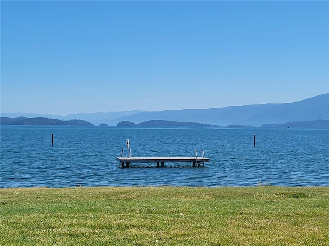 view of dock with a water and mountain view and a yard