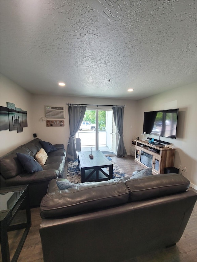 living room with a wall unit AC, a textured ceiling, and hardwood / wood-style flooring