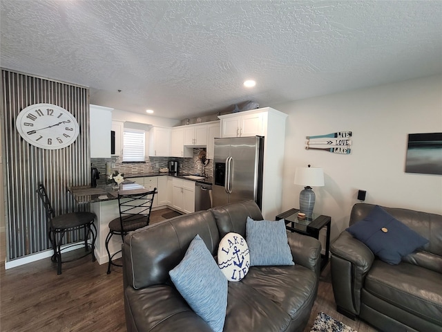 living room featuring dark wood-type flooring, sink, and a textured ceiling