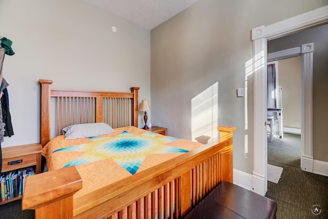 carpeted bedroom with a baseboard heating unit and lofted ceiling