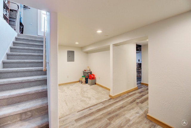 stairway featuring electric panel and wood-type flooring