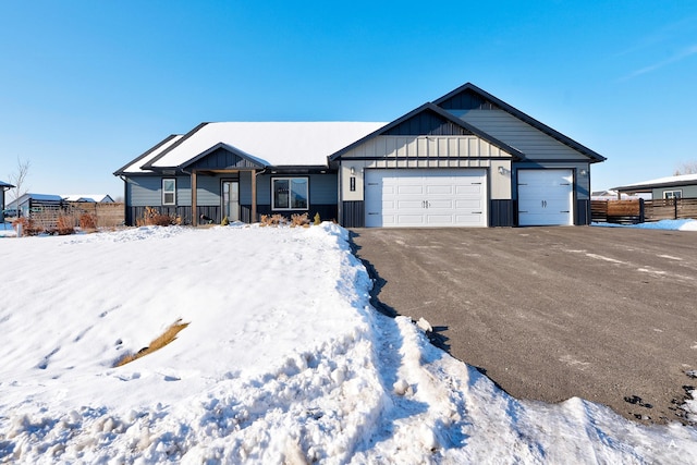 ranch-style home featuring a garage, driveway, fence, and board and batten siding