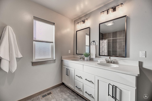 bathroom featuring double vanity, a sink, visible vents, and baseboards