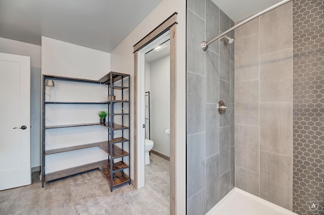 full bath featuring a tile shower, toilet, and baseboards