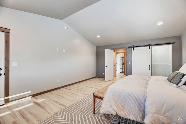 bedroom featuring lofted ceiling, baseboards, light wood finished floors, and a barn door