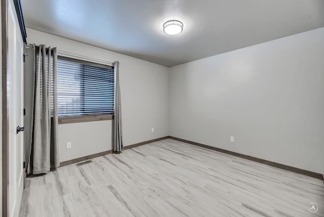 spare room with light wood-style flooring, visible vents, and baseboards