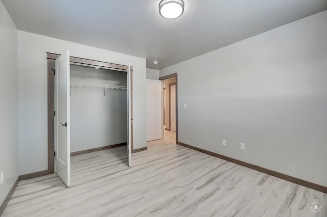 unfurnished bedroom with light wood-style floors, baseboards, and a closet