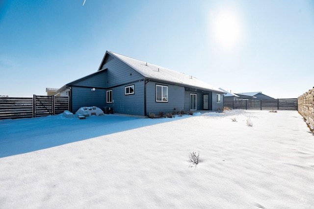 snow covered house with a fenced backyard