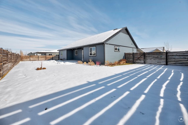 snow covered rear of property featuring a fenced backyard