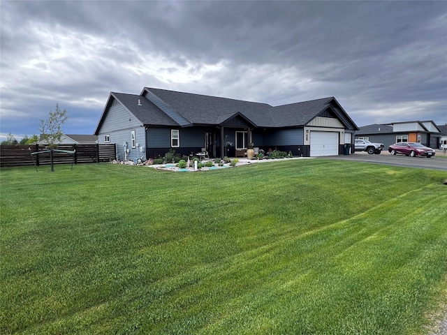 ranch-style house featuring aphalt driveway, a shingled roof, an attached garage, fence, and a front lawn