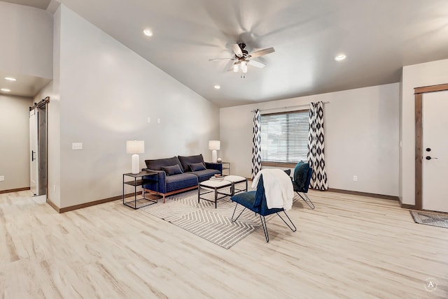 living room featuring light wood-type flooring, vaulted ceiling, ceiling fan, and a barn door