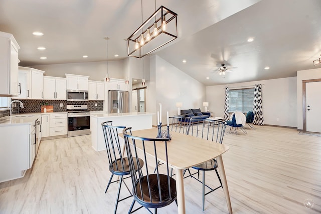 dining space featuring light wood finished floors, lofted ceiling, recessed lighting, ceiling fan, and baseboards