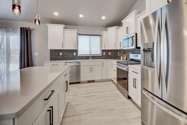 kitchen featuring a sink, white cabinets, appliances with stainless steel finishes, backsplash, and pendant lighting