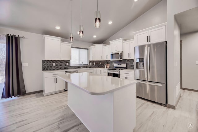 kitchen with stainless steel appliances, a sink, white cabinets, hanging light fixtures, and a center island