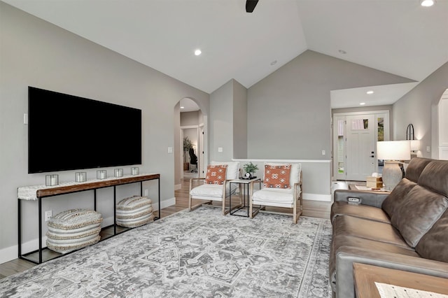 living room featuring light wood-type flooring, ceiling fan, and vaulted ceiling