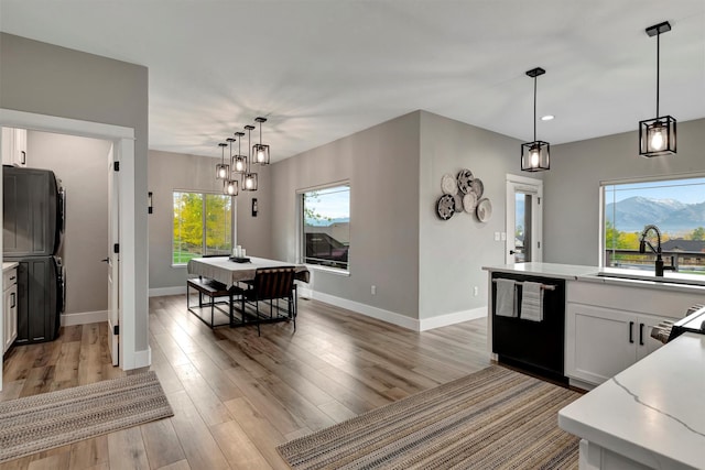 kitchen with black dishwasher, pendant lighting, white cabinets, and sink