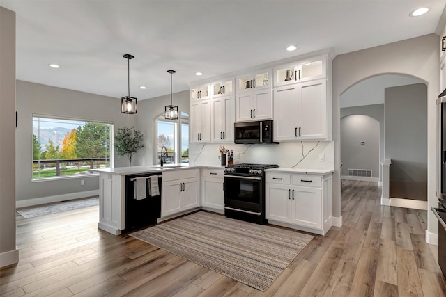 kitchen featuring white cabinets, black appliances, decorative light fixtures, backsplash, and kitchen peninsula