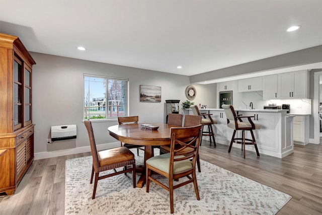 dining area featuring light wood-type flooring, heating unit, and sink