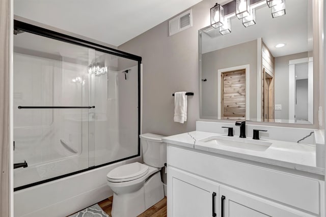 full bathroom with toilet, hardwood / wood-style flooring, vanity, and shower / bath combination with glass door