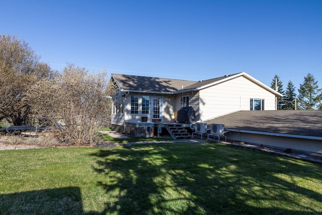 rear view of house with a lawn and roof with shingles