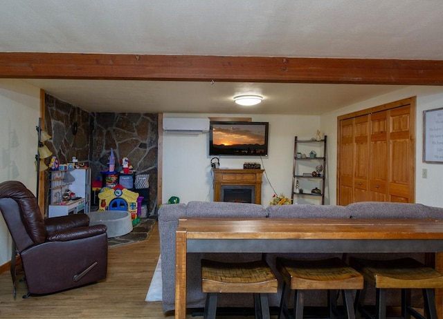 dining room featuring beamed ceiling, wood finished floors, a fireplace, and an AC wall unit