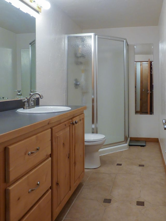 bathroom with a shower stall, toilet, vanity, and tile patterned floors