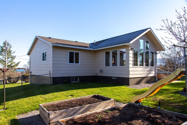 view of side of home with a garden, fence, and a lawn