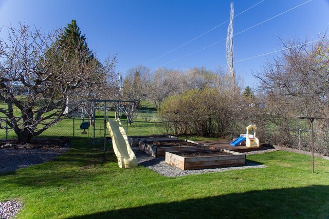 view of yard with a garden, a playground, and fence