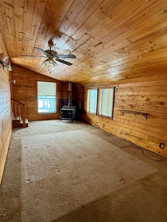 bonus room with lofted ceiling, ceiling fan, wood walls, a wood stove, and wooden ceiling