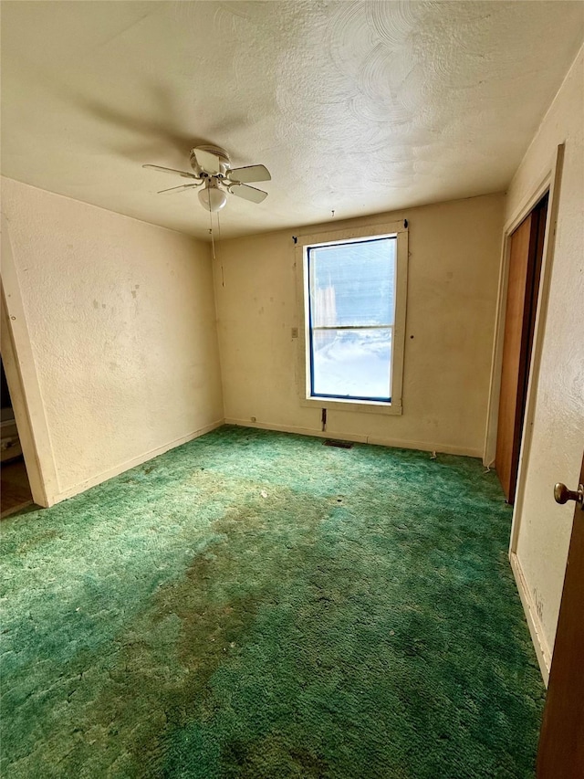 carpeted empty room featuring ceiling fan and a textured ceiling