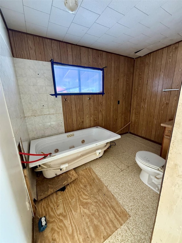 bathroom with toilet, wooden walls, and a washtub