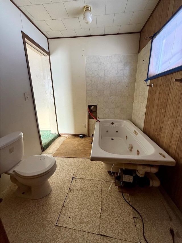 bathroom featuring wood walls, toilet, and a bathing tub