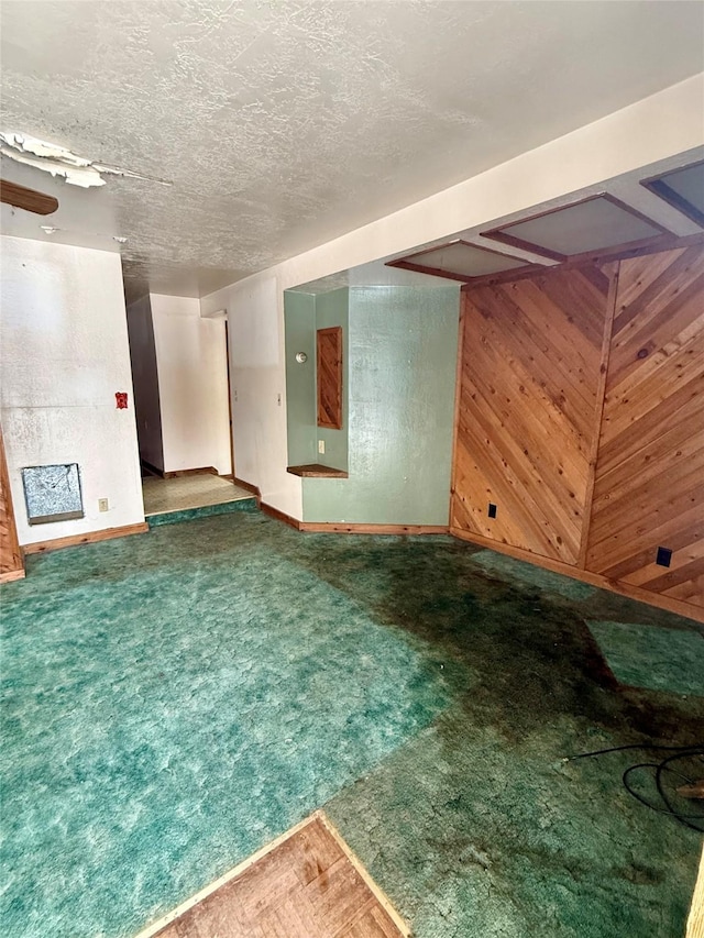 interior space featuring a textured ceiling, carpet flooring, and wooden walls