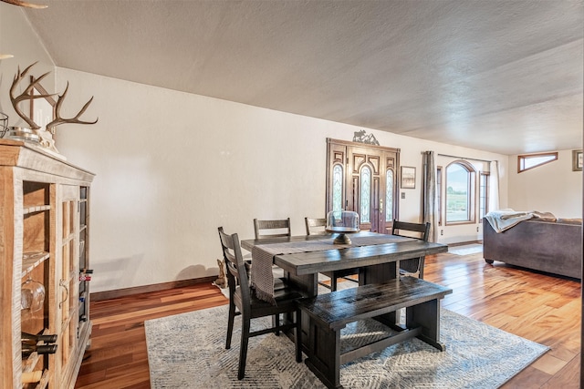 dining space with hardwood / wood-style floors and a textured ceiling