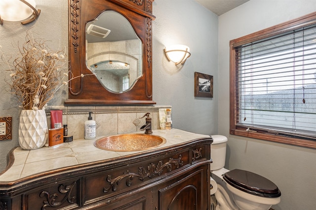 bathroom with toilet, vanity, and decorative backsplash