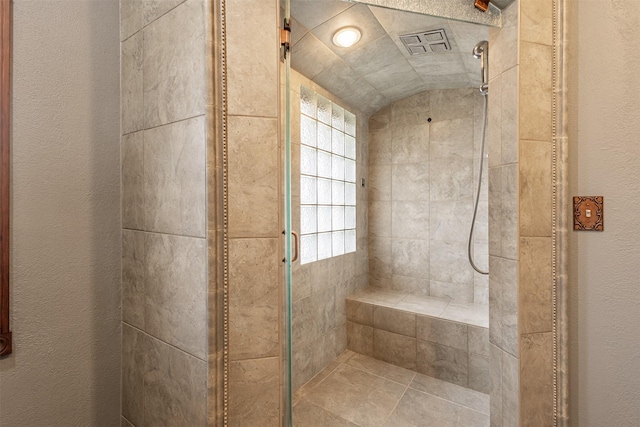 bathroom with a tile shower and vaulted ceiling