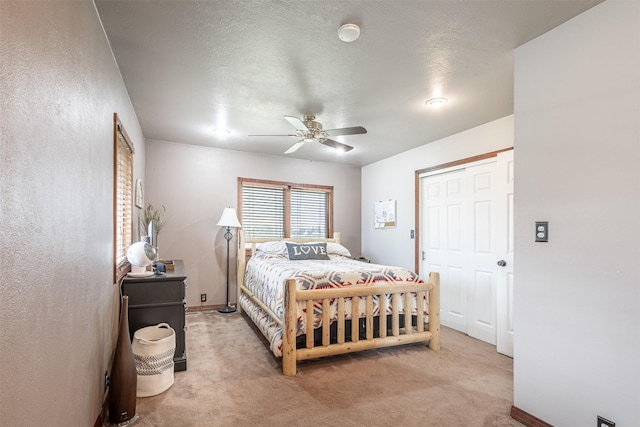 bedroom featuring ceiling fan, light carpet, a closet, and a textured ceiling